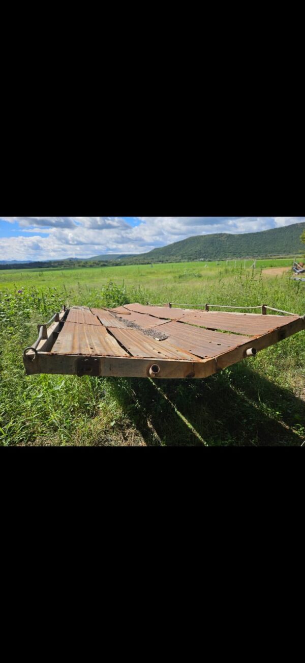 Used 6m Bale Trailer for transporting round and square hay bales or irrigation pipes, shown on grassy farmland with mountain background